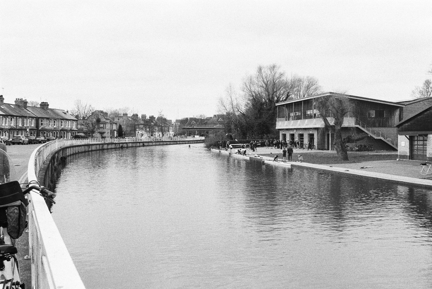 Rowing crews dawdling outside combined boathouse.