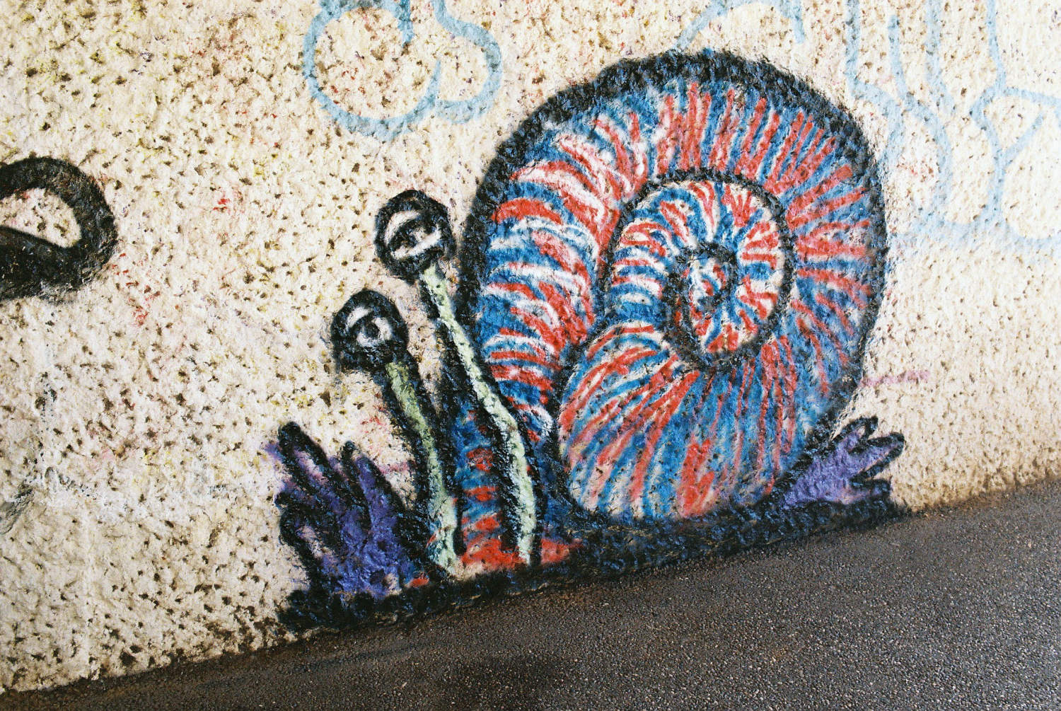 Graffito under Elizabeth Way bridge depicting a multicoloured snail.