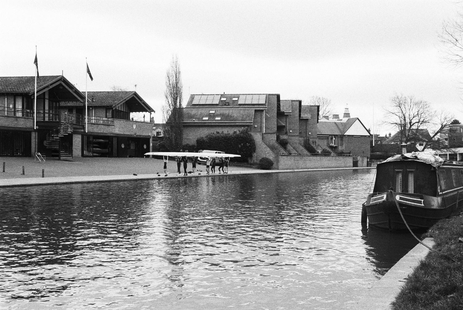 Students lifting boat outside Queens boathouse.